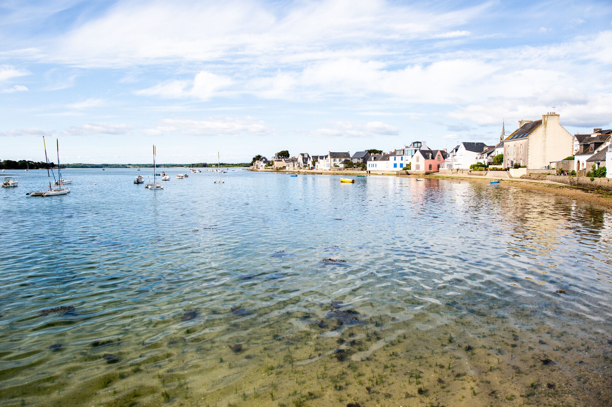 A coastal town with clear waters, boats, and traditional buildings along the shore.