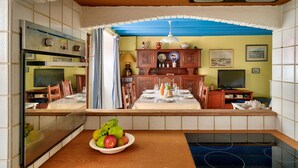 A kitchen with a dining area, a built-in oven, a television, and a fruit bowl on the counter. - 250m from the beach, house for 6, Île Tudy (Ile Tudy)