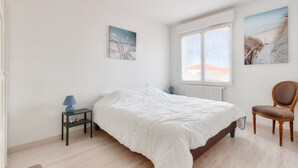 A bedroom with a large bed, a chair, a nightstand, and two wall-mounted lamps. - House for 8 – Les Sables – 950m from beach (Les Sables-d´Olonne)