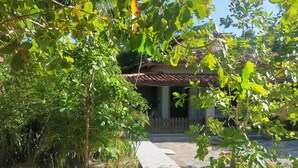 A paved pathway leading to a building with a tiled roof. - Cozy vacation home surrounded by greenery a few steps from the sea (Itaparica)