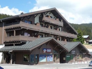 Un immeuble à plusieurs étages doté de balcons, d'un télésiège et d'une enseigne indiquant un restaurant.