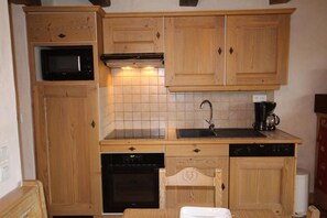 Une cuisine compacte dotée d’armoires en bois, d’un four à micro-ondes, d’une cuisinière, d’un évier et d’un lave-vaisselle.