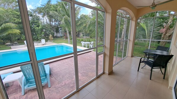 Una habitación con amplios ventanales que dan a una piscina y un jardín.