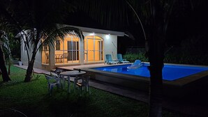 Une maison moderne dotée d’une piscine, d’un espace extérieur aménagé et d’un patio bien éclairé.