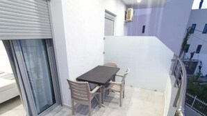 Un balcó amb una taula i cadires, una porta corredissa de vidre i vista a la ciutat.
