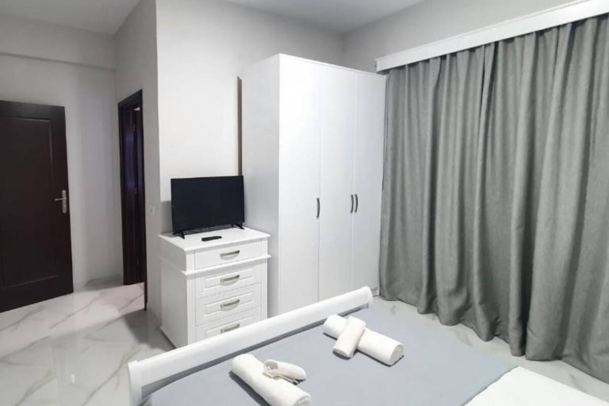 A hotel room with a bed, a wardrobe, a television, and a window with curtains.