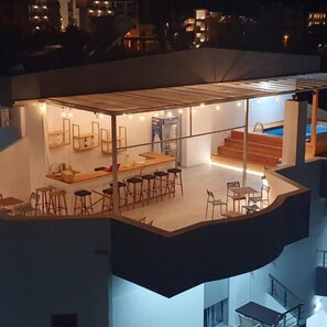 A modern, multi-level residential building with a rooftop terrace featuring a dining area, bar, and pool. - IL MIO (Ksamil)
