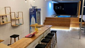 Zona de bar moderna amb tamborets de fusta i una barra llarga.