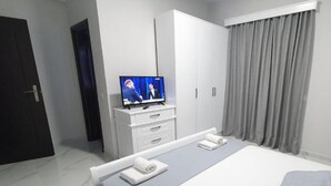 Habitació d'hotel moderna amb un llit gran, televisió de pantalla plana, armari i porta al bany.