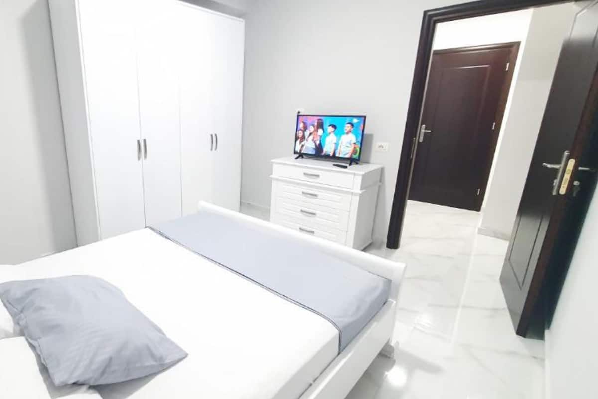 A bedroom with a bed, a TV on a dresser, and a wardrobe.