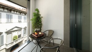 A balcony with a table, chairs, a potted plant, and a view of buildings.