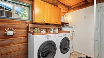 A laundry area with a washing machine and dryer, wooden cabinets, a window, and a towel rack.