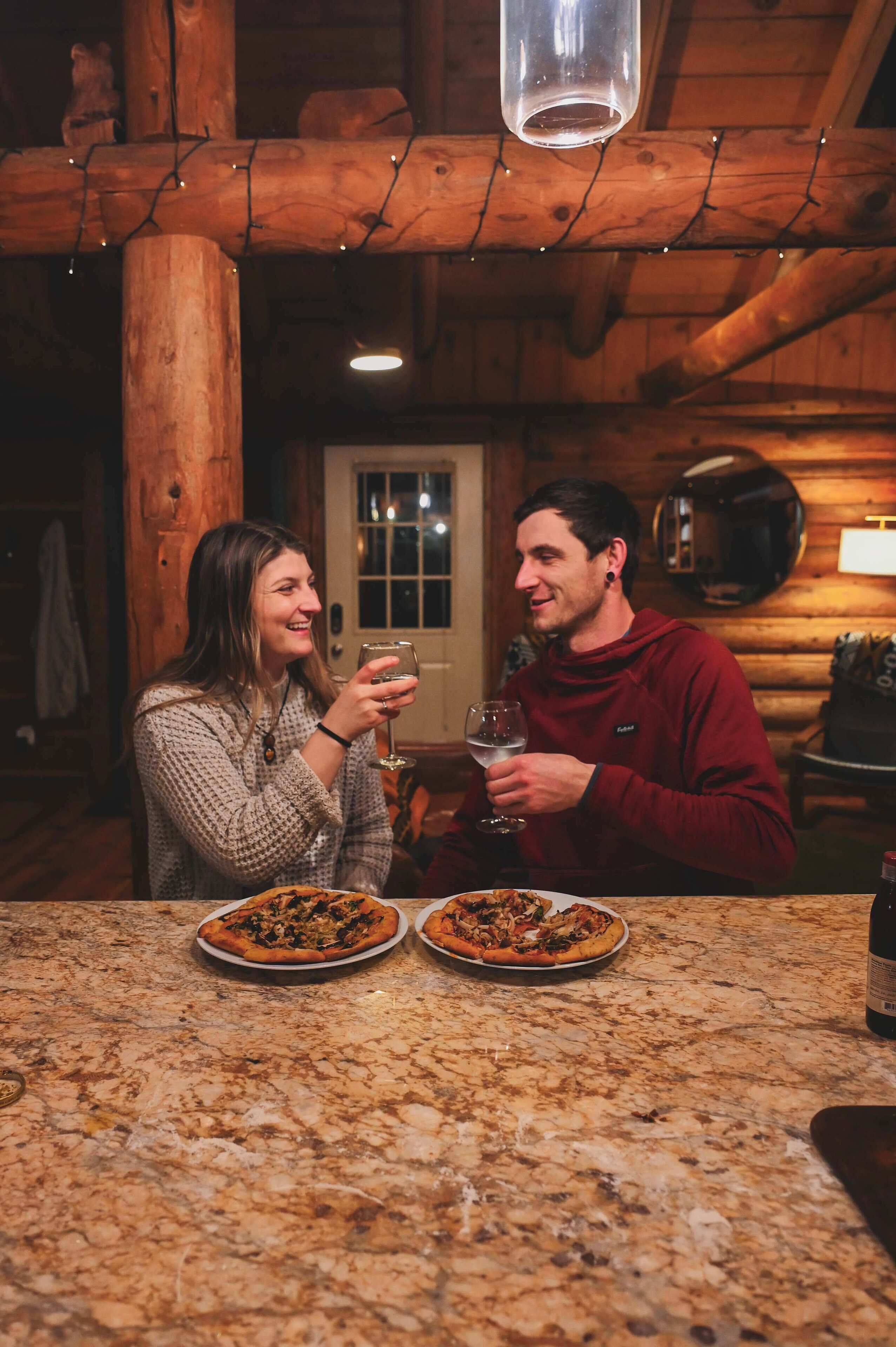 A wooden interior with a marble countertop, two pizzas, and a bottle.