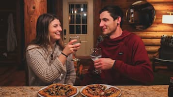 A wooden interior with a marble countertop, two pizzas, and a bottle.