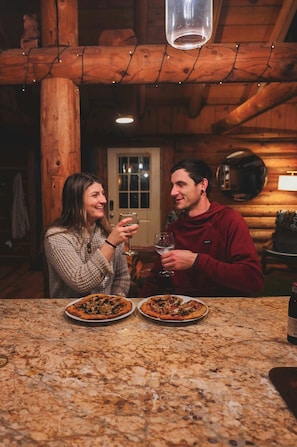 Un interior de madera con encimera de mármol, dos pizzas y una botella.
