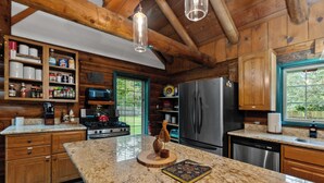 Cocina con paredes de madera, encimeras de granito, electrodomésticos de acero inoxidable y vistas al exterior.