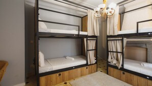 Habitación con literas, candelabro, cortinas y piso estampado.