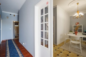 Un couloir avec un tapis bleu, une porte blanche et un coin repas comprenant une table et des chaises blanches.