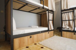 A bunk bed room with a wooden lower bunk, a mattress, and a headboard.