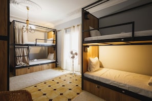 A room with bunk beds, a fan, a chandelier, and a patterned floor.