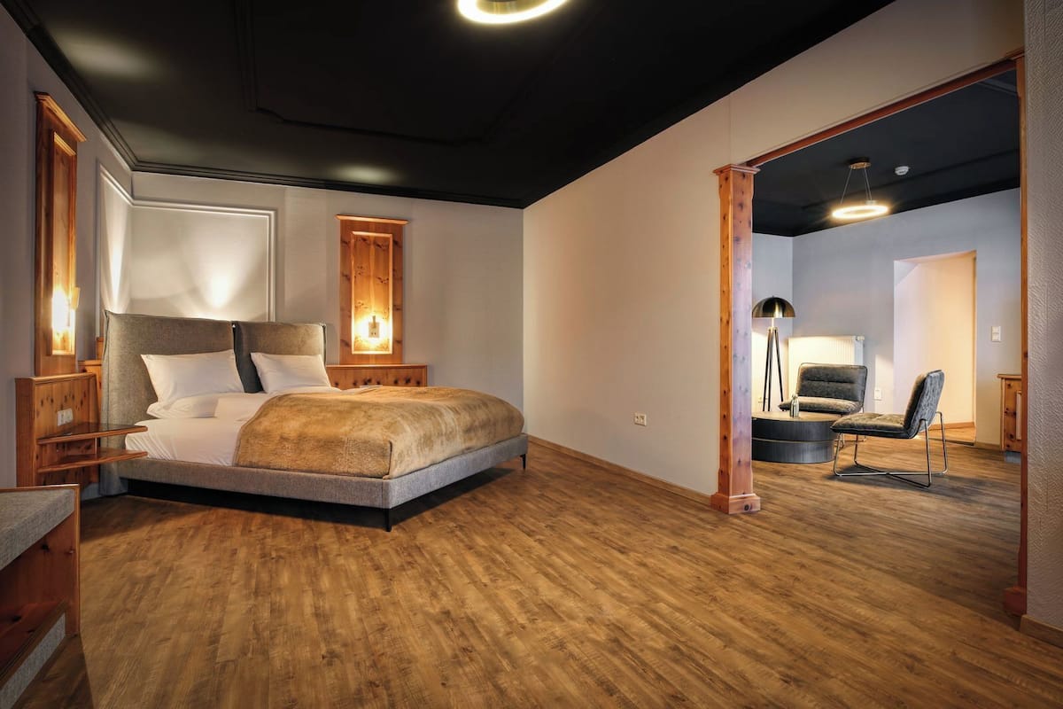 Ein modernes Schlafzimmer mit einem großen Bett, einem Holzkopfteil und einem Nachttisch mit Lampe.