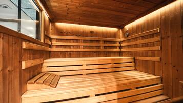 A wooden sauna with benches and a clock on the wall.