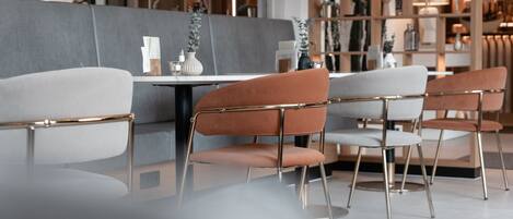 A modern interior with a grey sofa, a white table, and orange chairs with metal frames.