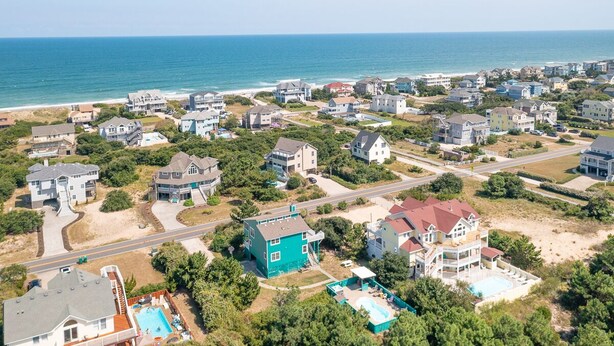 An aerial view of a coastal residential area with houses, roads, and a beach. - Pet-friendly oceanside Corolla home w/ private pool & hot tub! (Corolla)