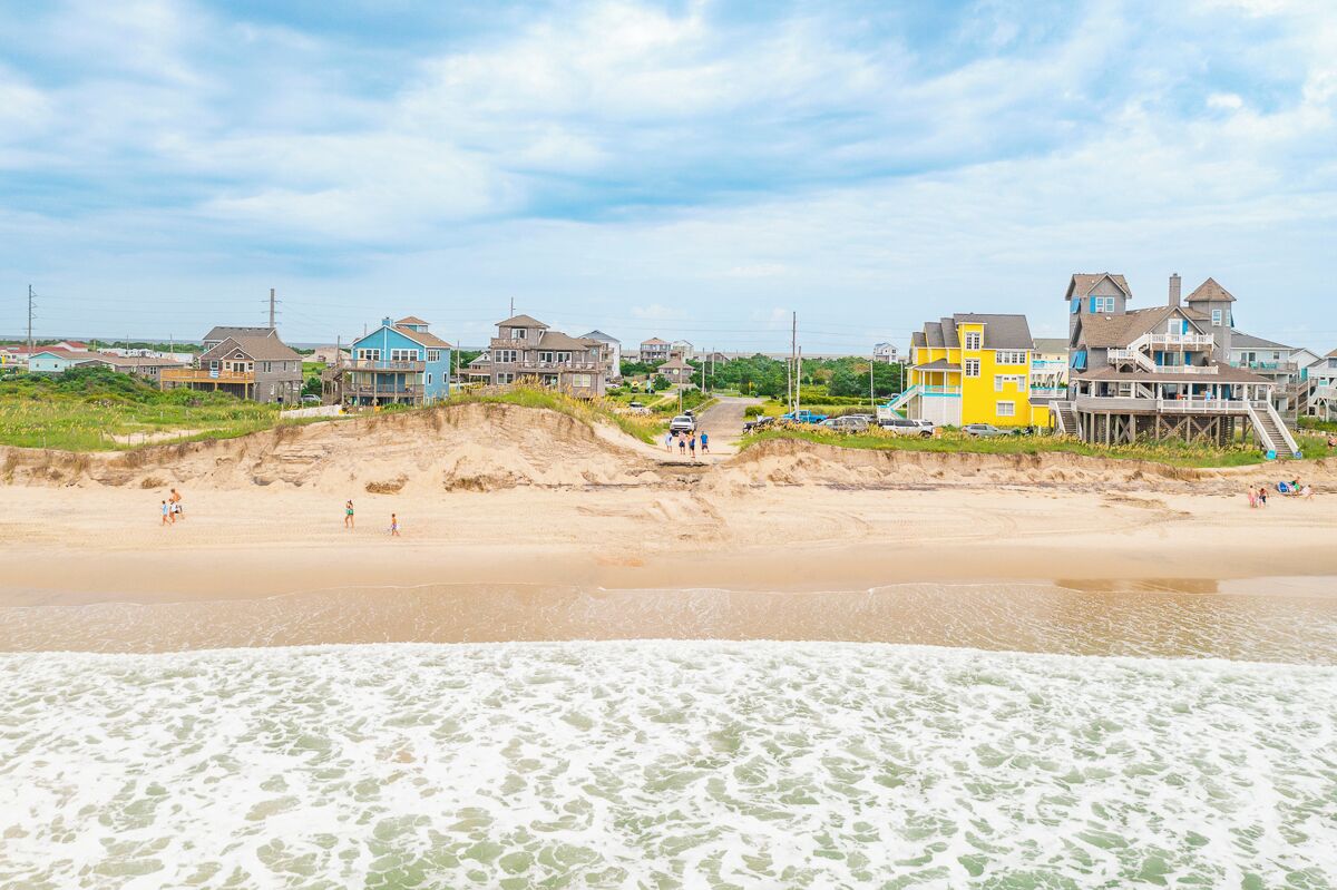 Une zone résidentielle côtière avec des maisons, une plage de sable et une jetée.
