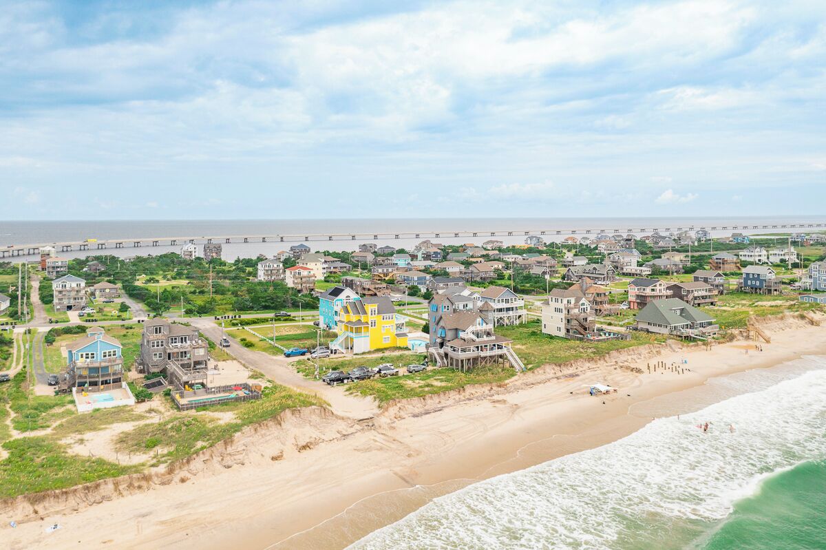 Une zone résidentielle côtière avec des maisons, une plage et un pont en arrière-plan.