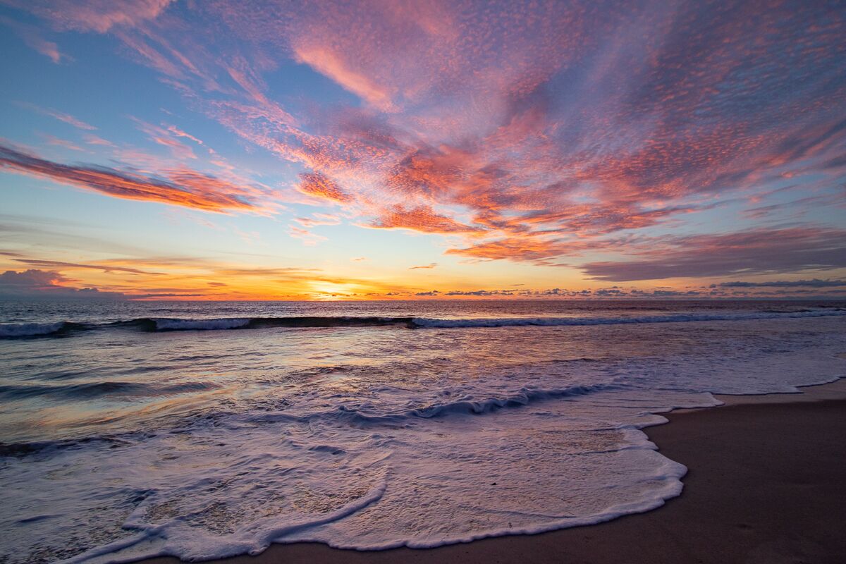 A beach with waves at sunset.