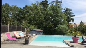 A backyard with a swimming pool, lounge chairs, and a small shed.