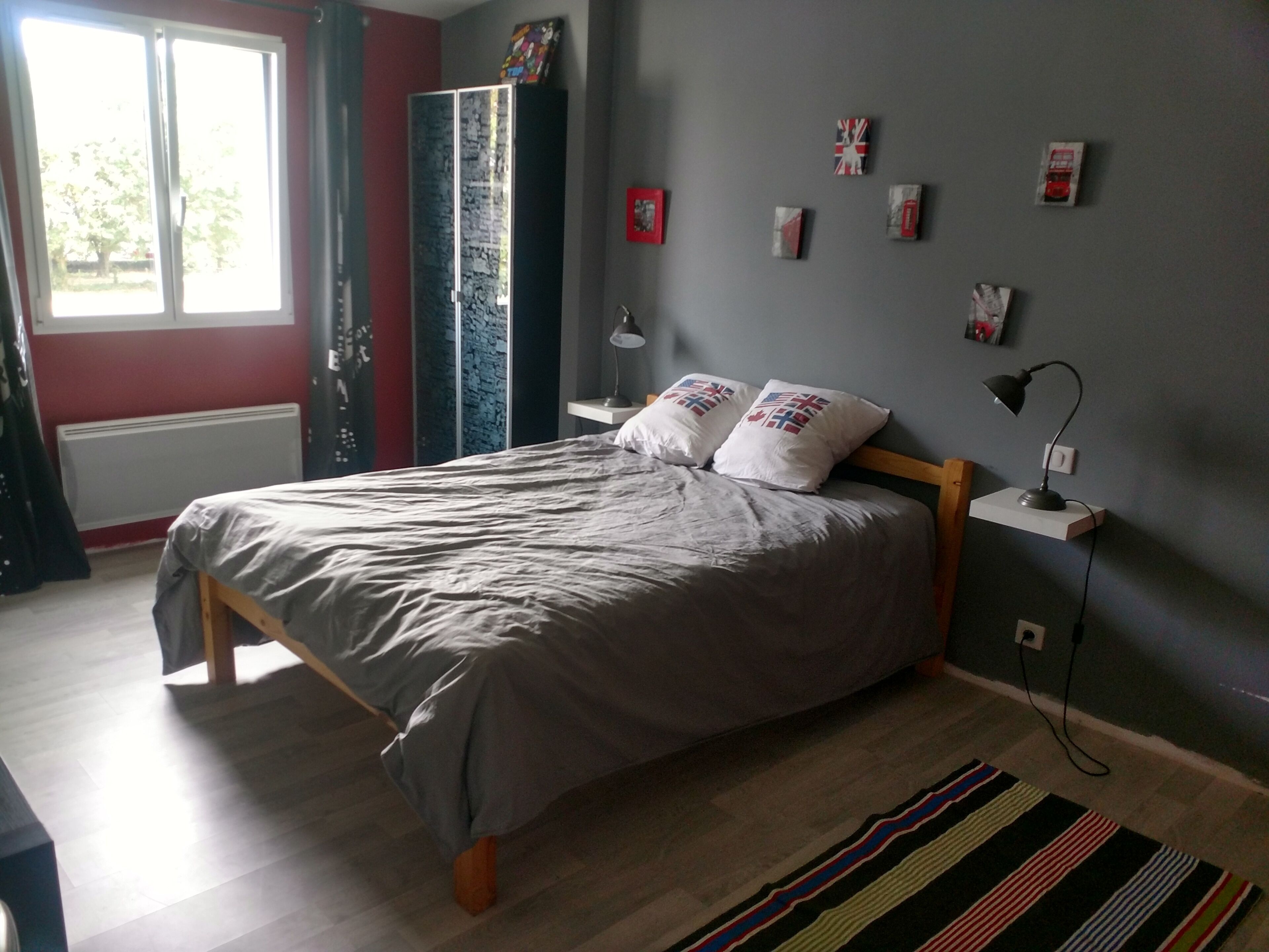 A bedroom with a bed, a nightstand, a lamp, and a window.