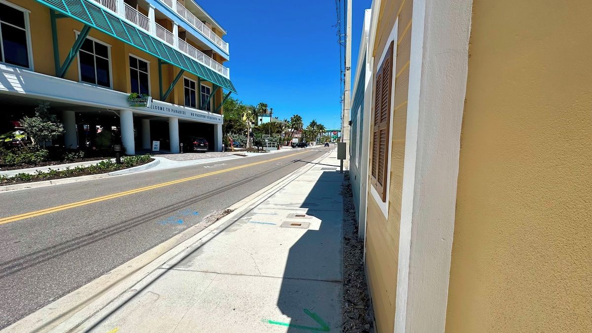 A street view with a building featuring a balcony and a sign that reads 'Welcome to Paradise.'