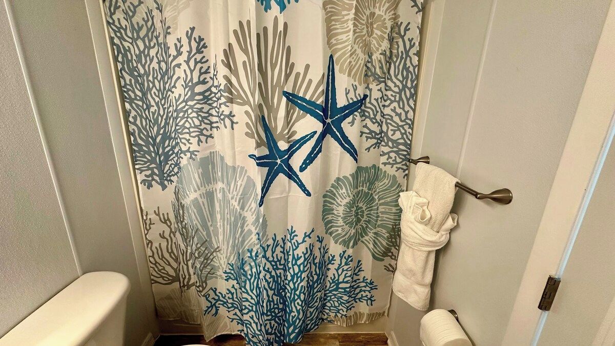 A bathroom with a shower curtain featuring a coral reef design, a toilet, and a towel rack.