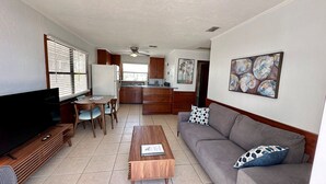 A living room with a TV, a coffee table, a sofa, and a dining area with chairs. - One Particular Cottage - Next to Margaritaville (Fort Myers Beach)