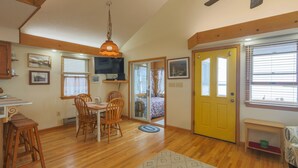 A dining area with wooden chairs and a table, a yellow door, and a television on the wall. - Mallard Island home.  located at 1375 e mallard dr Manahawkin 08087            (Stafford Township)