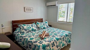 Een netjes opgemaakt bed met een bloemenbedekker, een houten hoofdbord en een bedlampje.