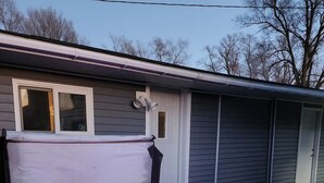 A hot tub with a built-in heater and LED lights, situated in a backyard with a house in the background. - Cabin in Oscoda with hot tub and game room

 (Oscoda)
