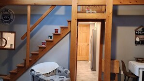 A wooden interior with a skylight, a staircase, a patterned ottoman, and a dining area. - Cabin in Oscoda with hot tub and game room

 (Oscoda)