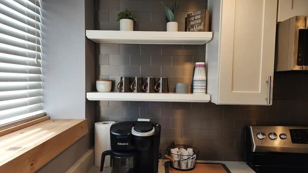 A kitchen with a Keurig coffee maker, a coffee mat, and a shelf with mugs and a sugar container. - Cabin in Oscoda with hot tub and game room

 (Oscoda)