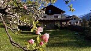 Une maison avec un toit en pente, une pelouse bien entretenue et une vue sur les montagnes en arrière-plan.