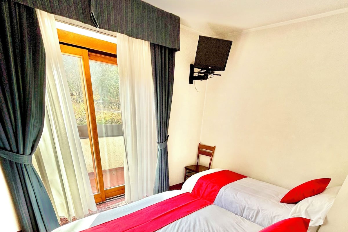 Hotellihuone, jossa on suuri sänky, tuoli, televisio ja näkymä ulos.