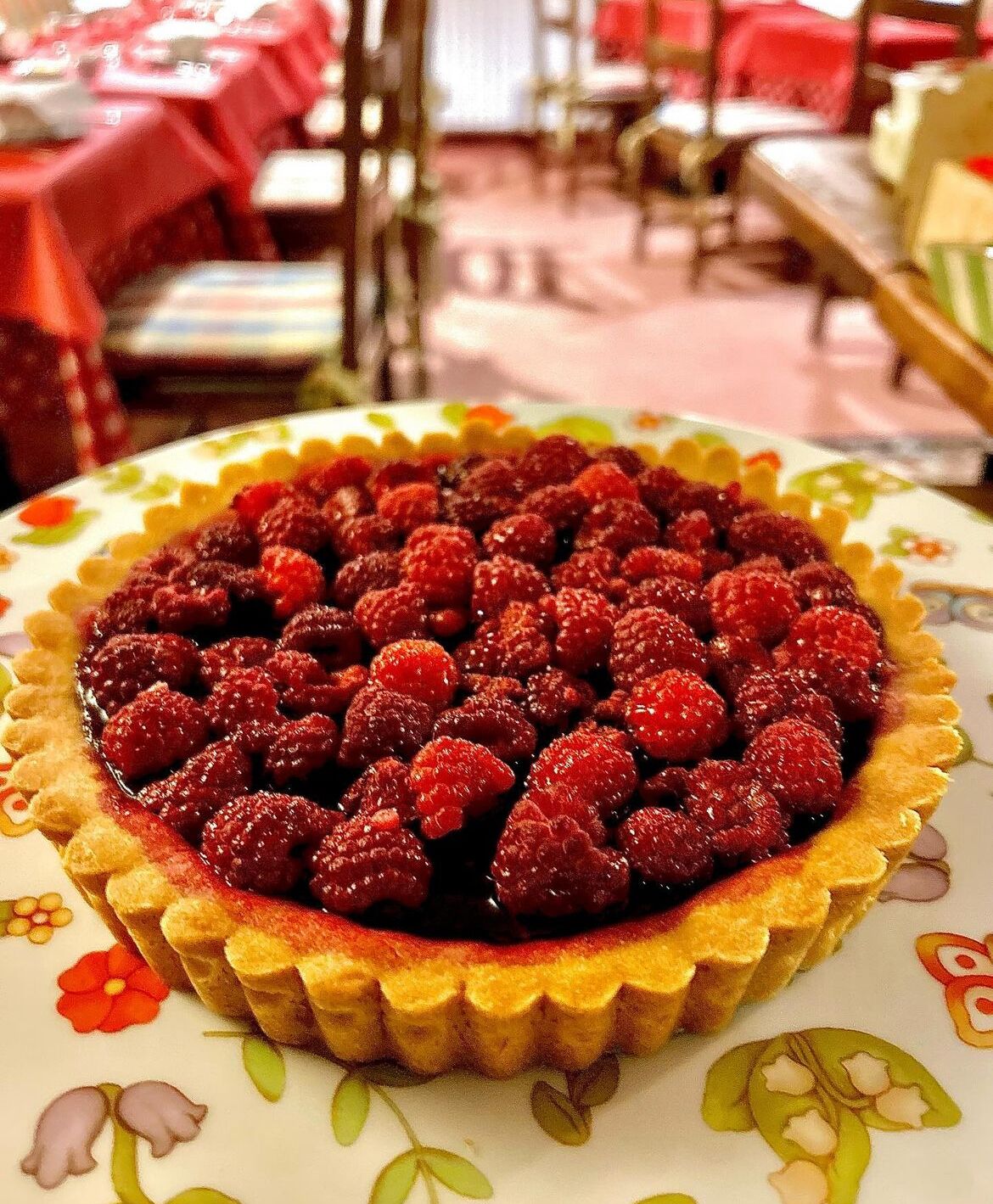 Una tartaleta de frambuesa sobre un plato estampado con motivos florales.