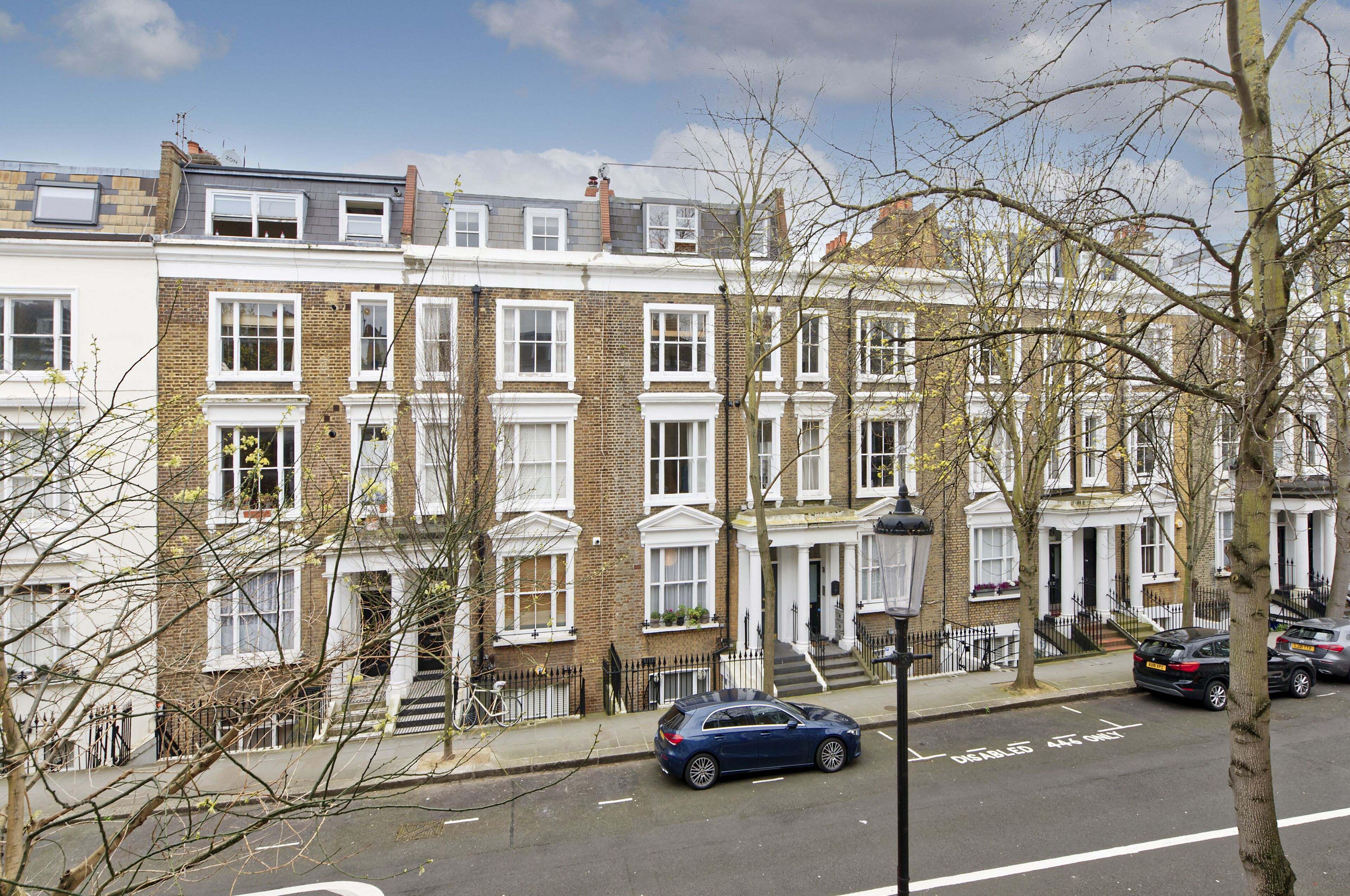 A row of terraced houses with a narrow street in front.