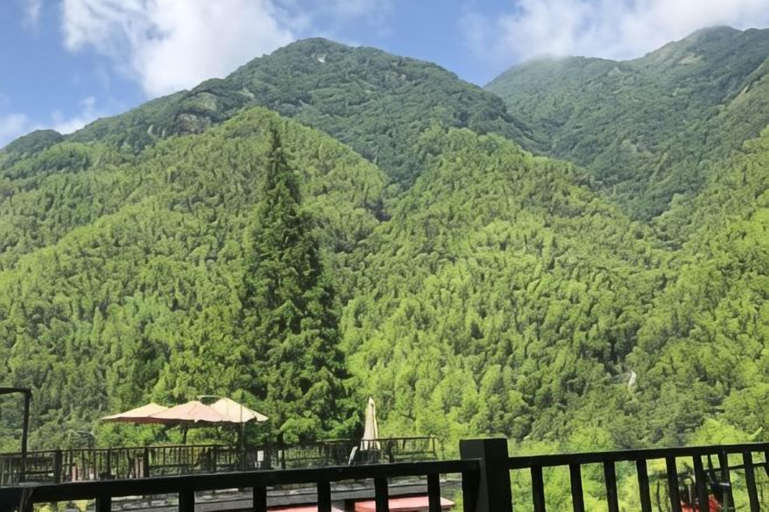 Paisagem montanhosa com vista para um edifício de telhado vermelho e um espaço de terraço.