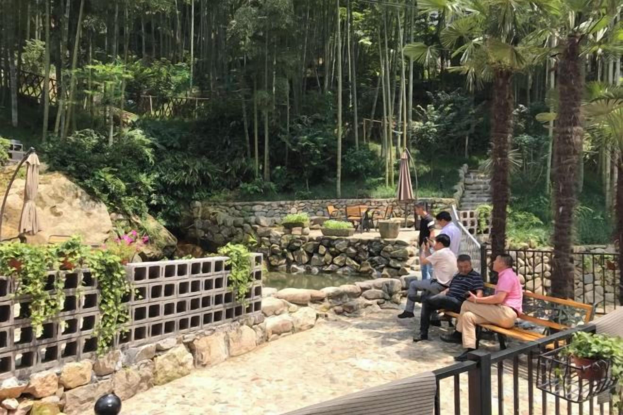 Ein Garten mit Teich, Sitzgelegenheit und Steinmauern.