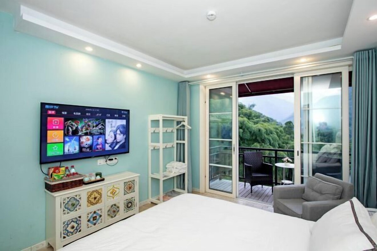 Une chambre d’hôtel avec un lit, une télévision, un balcon avec une chaise et une petite table.