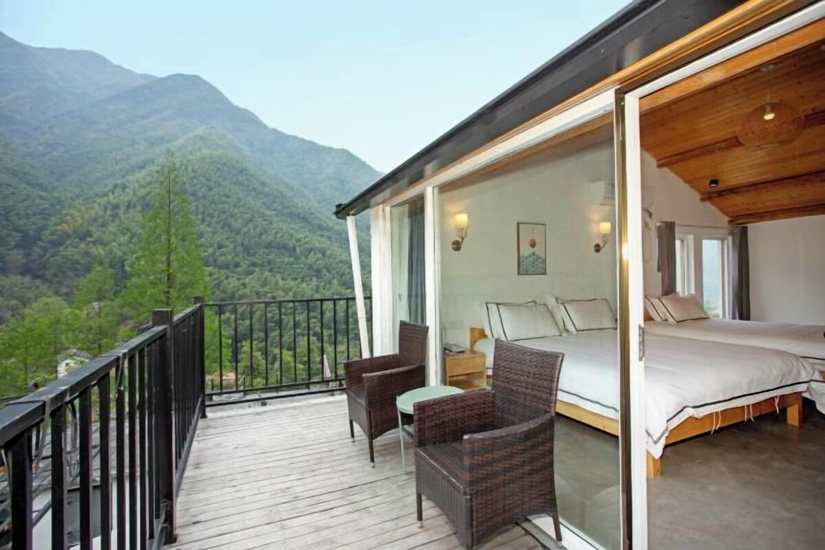 Un balcon avec des meubles en osier, un lit et une vue sur les montagnes.