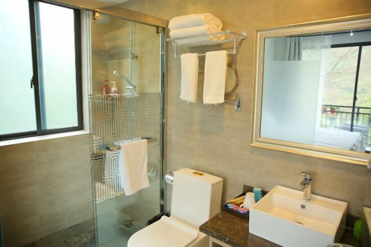 Une salle de bain avec une douche à parois de verre, des toilettes, un lavabo et un miroir.